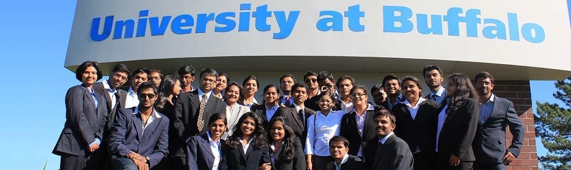 Group photo of students from India in front on a UB sign on their visit here. 