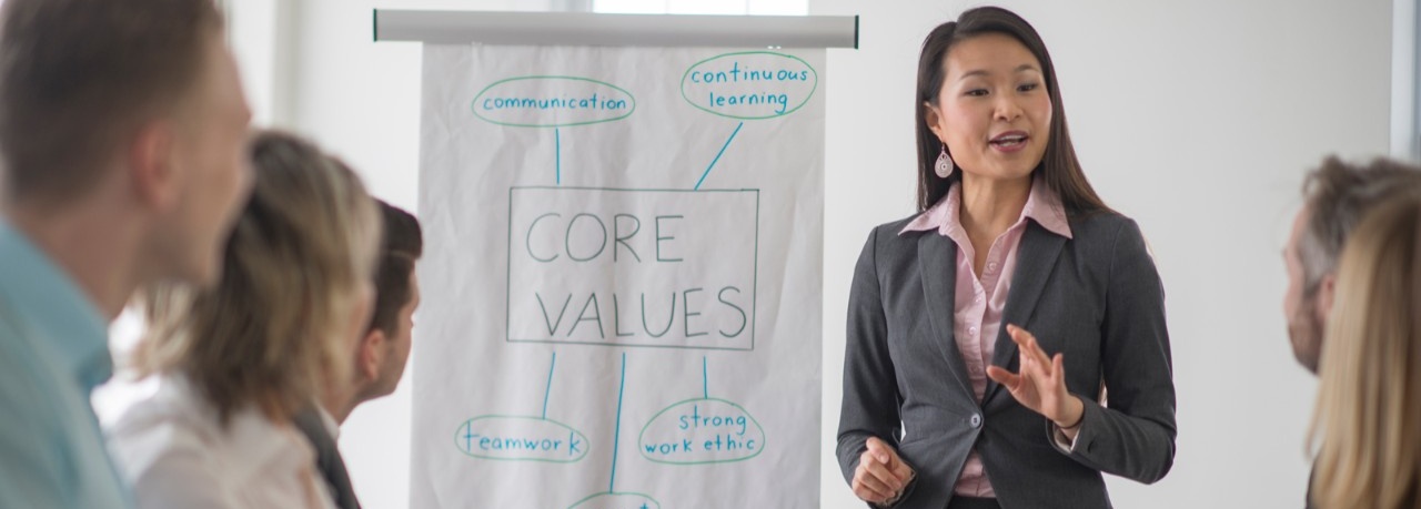 A woman discusses her company's core values with her team members. 