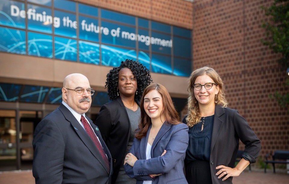 Four new faculty members stand outside Jacobs Management Center. Pictured, from left, are: Alan Katerinsky, Aisha O'Mally, Rose Hu and Nicole Zeftel. 