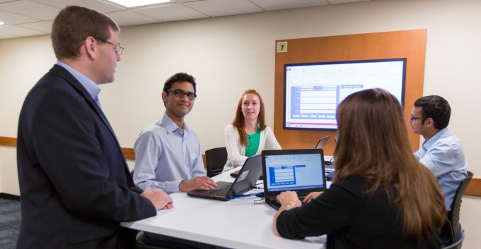 David Murray, faculty director for the new BS in Information Technology and Management program, works with four students on their laptops. 