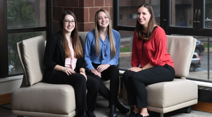From left, Women in Management e-board members Jenna Behm, Samantha Frank and Gabrielle Lindauer sit on chairs in Jacobs Management Center. 