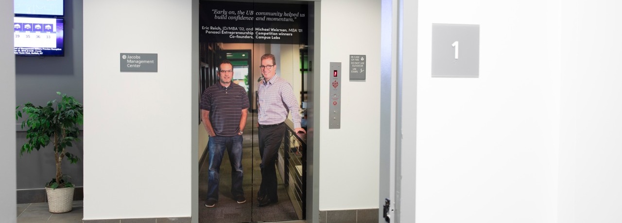 Zoom image: The elevators are wrapped with a photo of Eric Reich, JD/MBA ’02, and Michael Weisman, MBA ’01, co-founders of Campus Labs. The pair credits UB and the School of Management for being instrumental in their success and the visual reminds students that they are in an inclusive, supportive environment. 