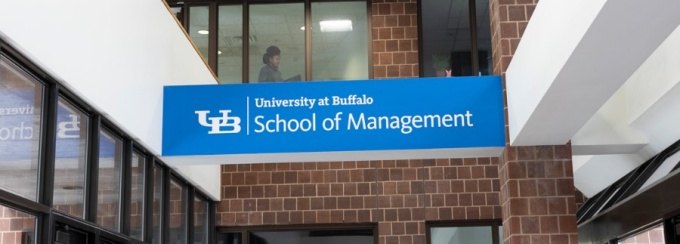 The entryway to Jacobs Management Center, with the School of Management logo on an overhead beam. 