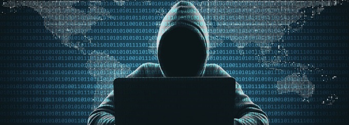 Shadowy person in a hoodie on a laptop. 