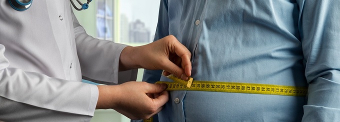Doctor measuring the waist of a patient. 