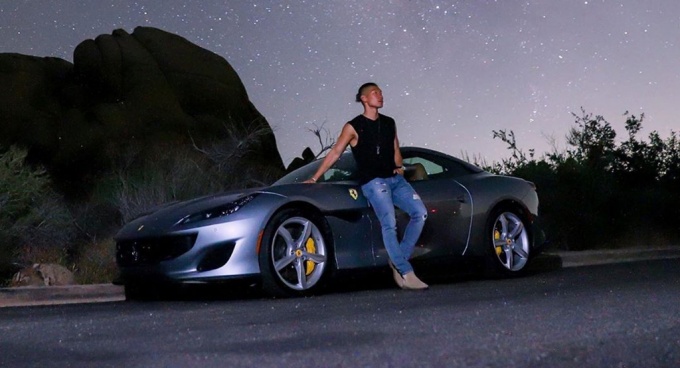 Chan outside posing with a car. 