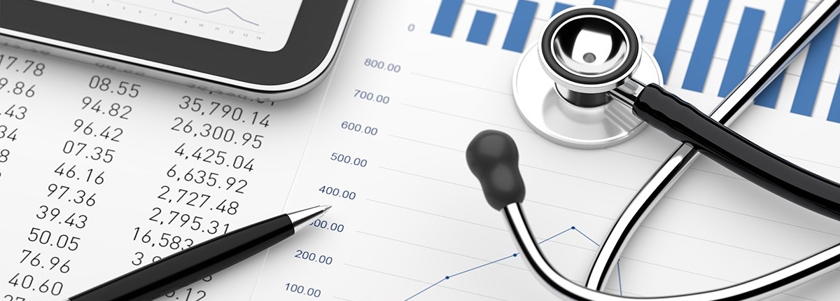 Stethoscope atop a spreadsheet with a tablet computer and pen.