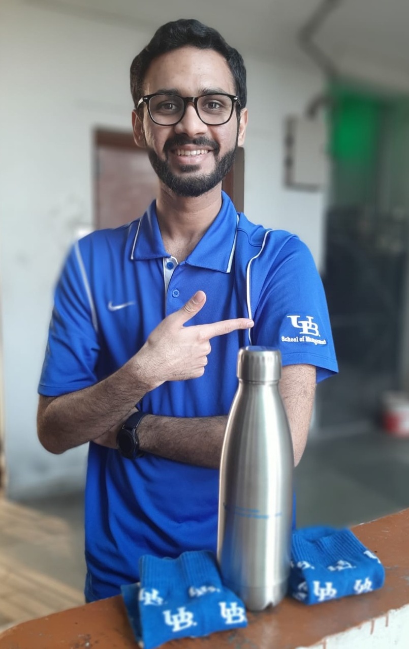 Zoom image: Siddharth Khandelwal shows off the new UB School of Management-branded polo, socks and water bottle he won. Access a larger version of this image.