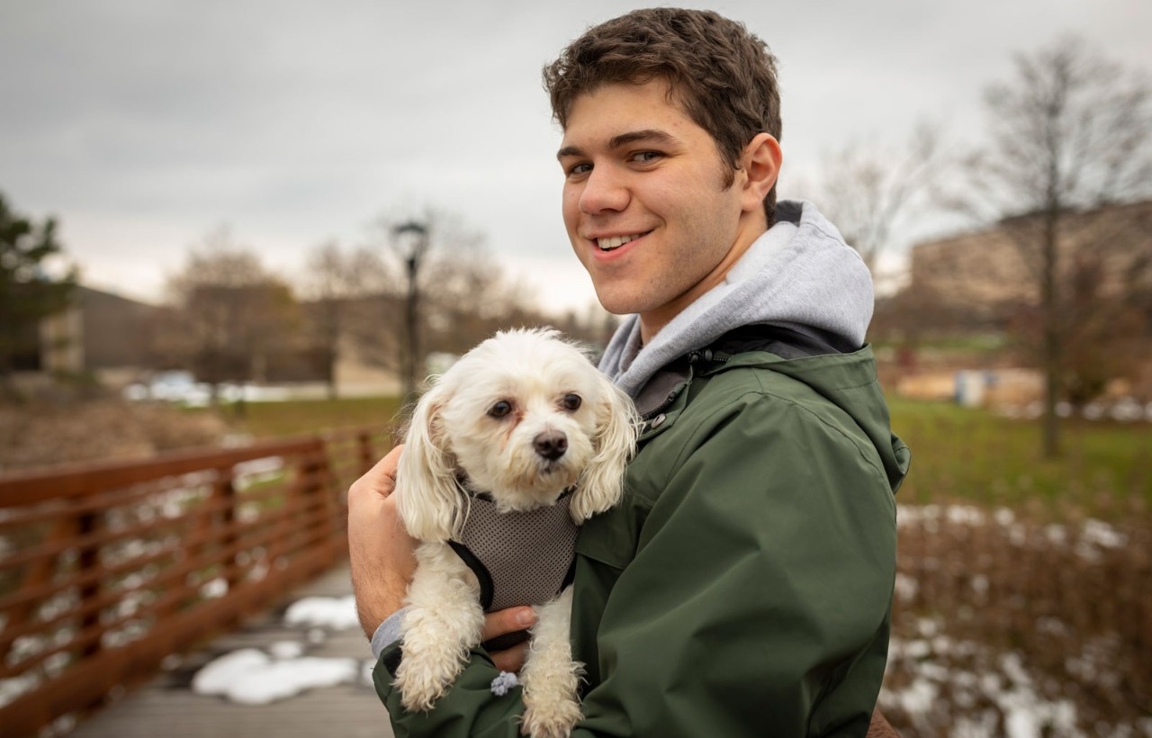 Michael Nejame, BS ’20, holds one of the dogs he walks, thanks to the smartphone app Rover. 