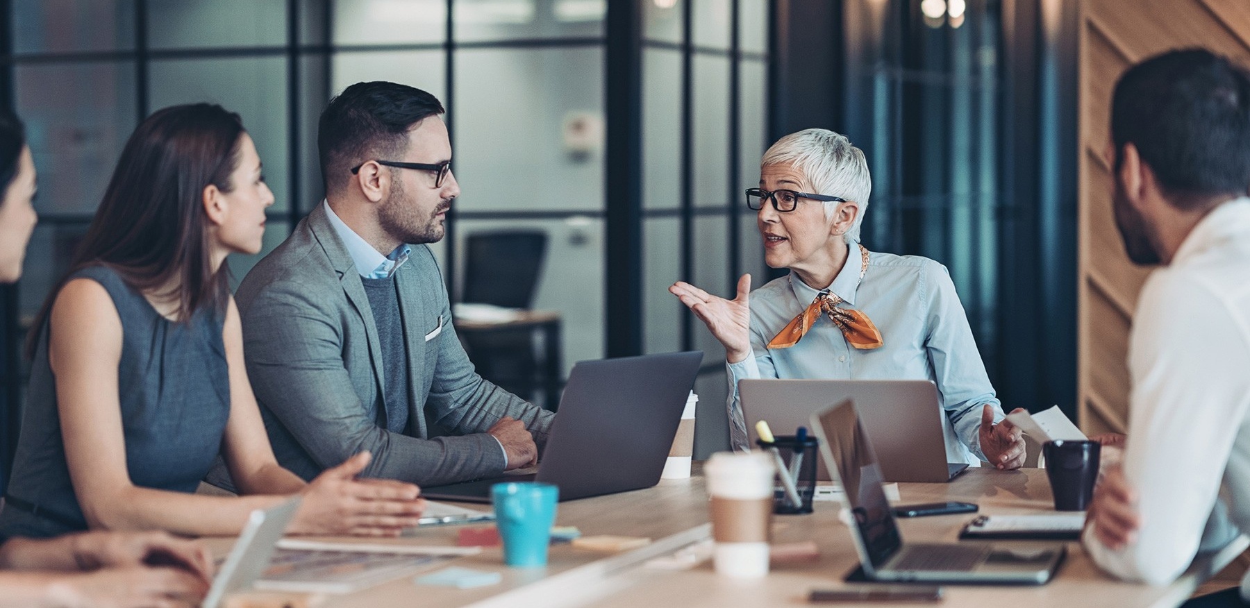 Manager speaking to employees at a conference table. 