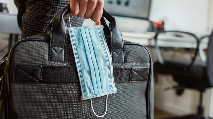 Person holding laptop bag and mask. 