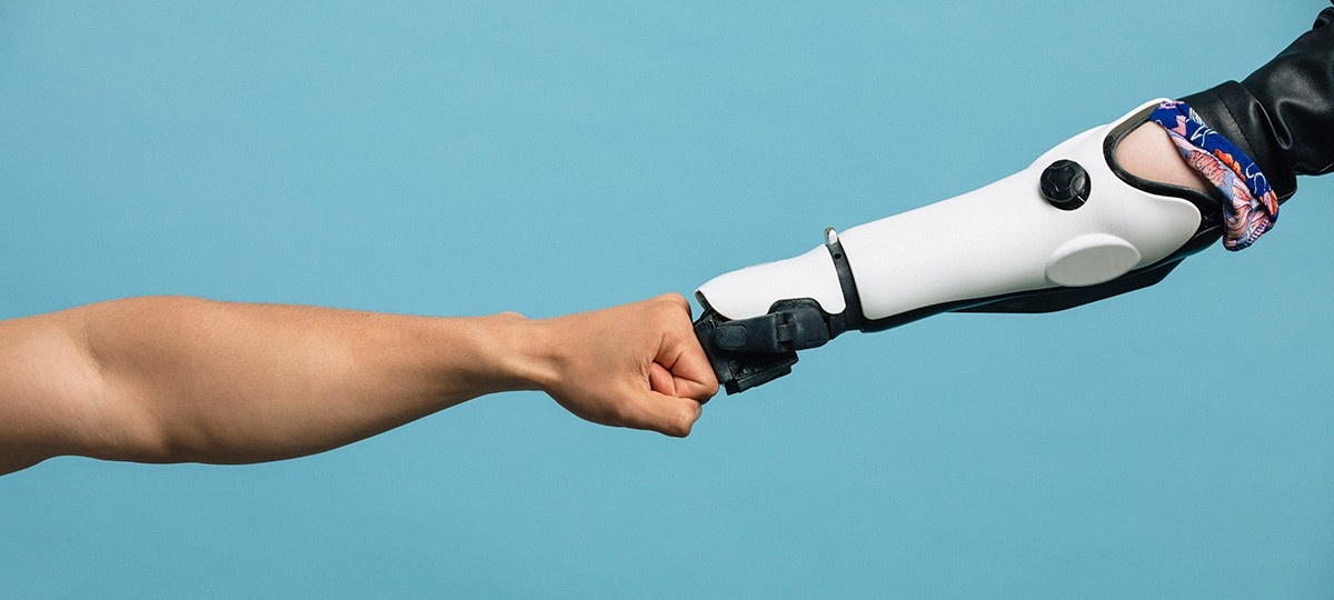 A human arm giving a fist bump to a robot arm. 