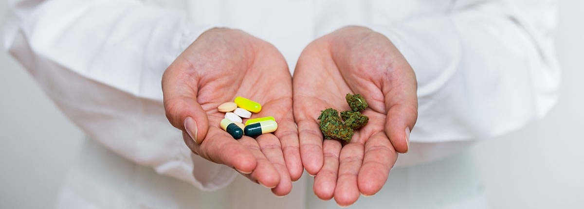 Doctor holding marijuana in one hand and pills in the other. 