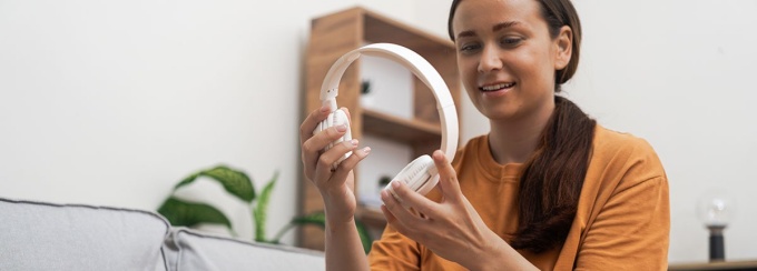 With joy, a woman unpacks her home-delivered package, revealing sleek modern headphones from an online store. 