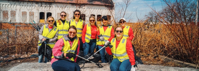 Rich's Products workers posing for pictures at cleanup site waering high-visibility vests and holding cleaning equipment. 