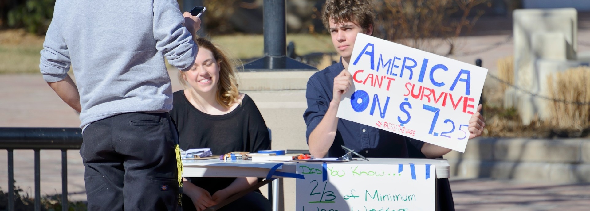 Boulder, Colorado, USA - February 19, 2014: Two young people explain why Americans can't survive on $7.25 minimum wager per hour in downtown Boulder.