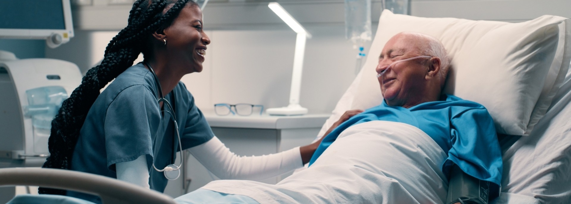 Patient talking to nurse while smiling in hospital bed.