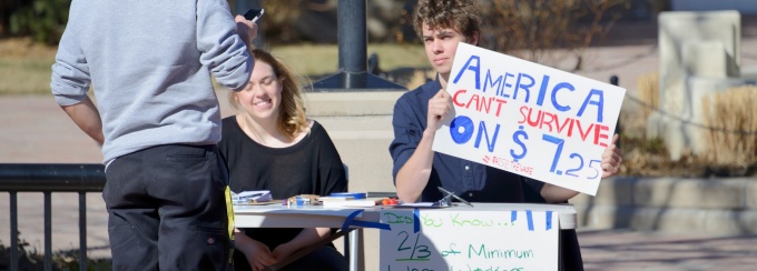 Boulder, Colorado, USA - February 19, 2014: Two young people explain why Americans can't survive on $7.25 minimum wager per hour in downtown Boulder. 