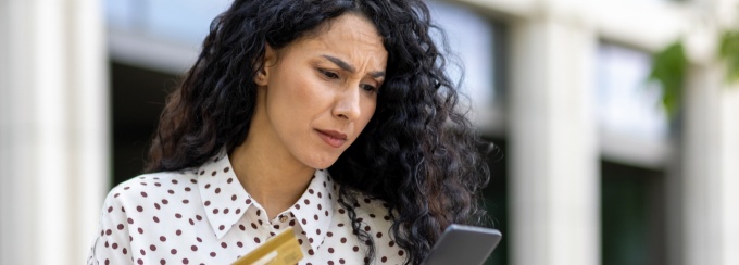 Person holding credit card and mobile device. 