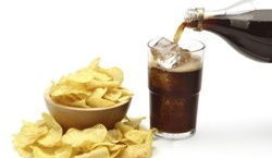 Soda pop and chips on a table. 