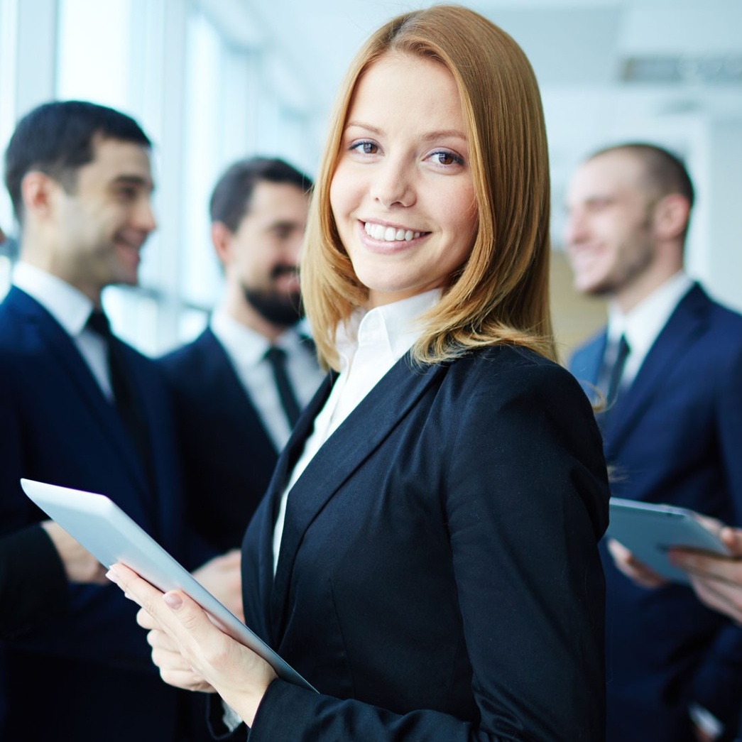 Group of students wearing dark suits, holding tablets. 