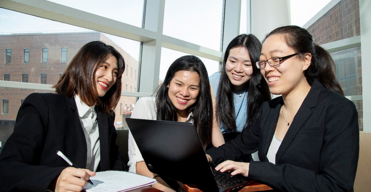 From left, Wei Wang, Joey Chen, Jeanna Huang and Jennifer Wu gather around a computer to work on their data analytics project. 