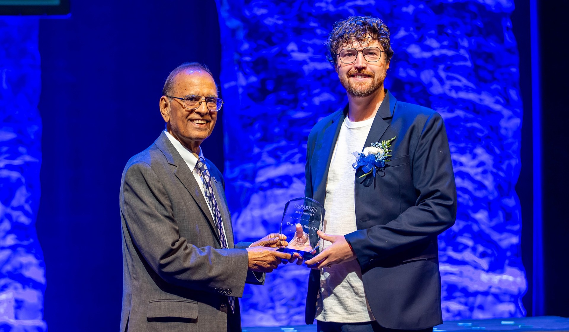 UB President Satish K. Tripathi shakes hands with Trevor Titley, co-founder of The Ticketing Co., while handing him a Fast 46 award. 