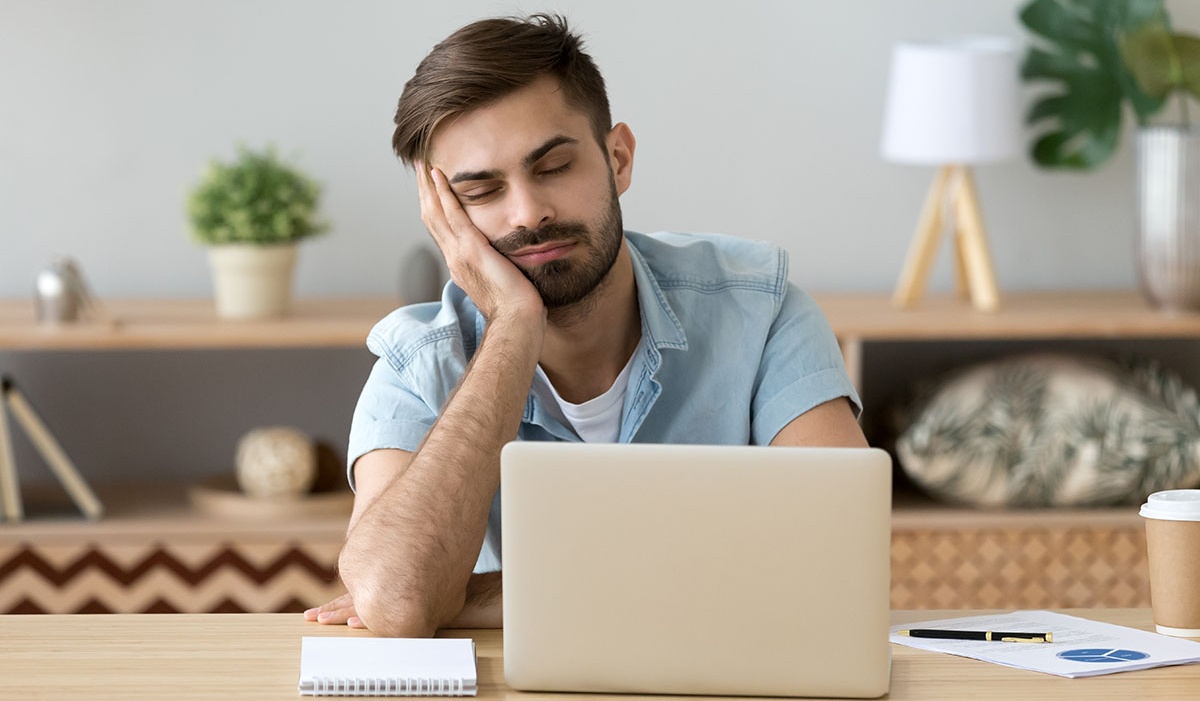 Man in front of computer looking bored. 