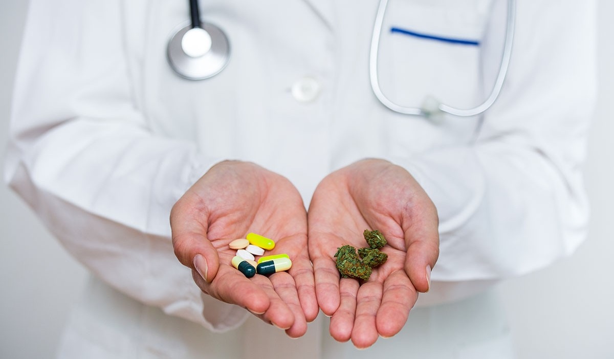 Physician holding pills in one hand and marijuana in the other. 