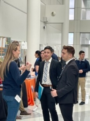 Business students in suits speaking to company representative at Career Expo in UB Center for the Arts. 