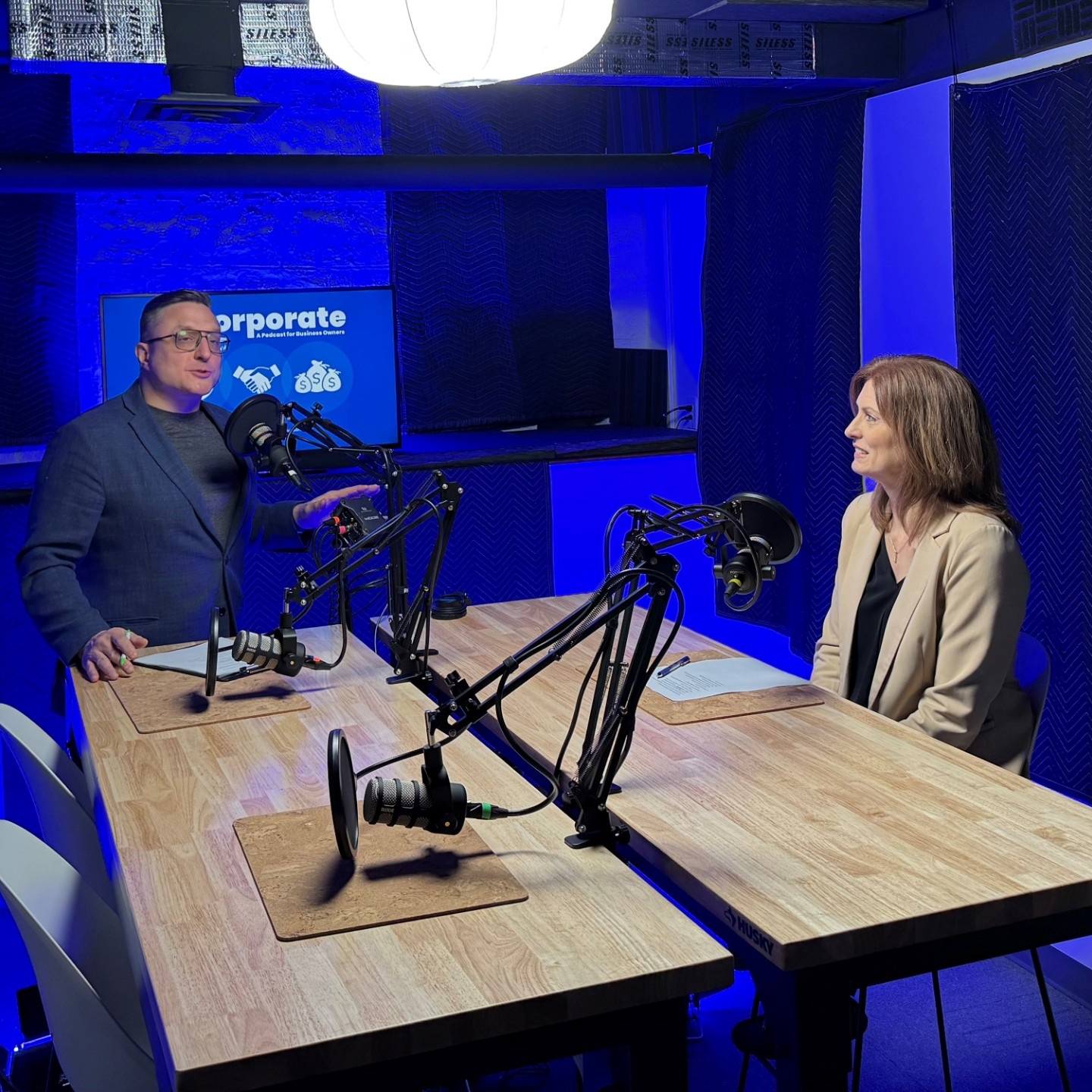Jordan Lema and Susan Steffan in a podcast sudio with microphones. 