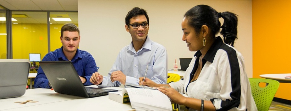 Three students sitting at a desk. 