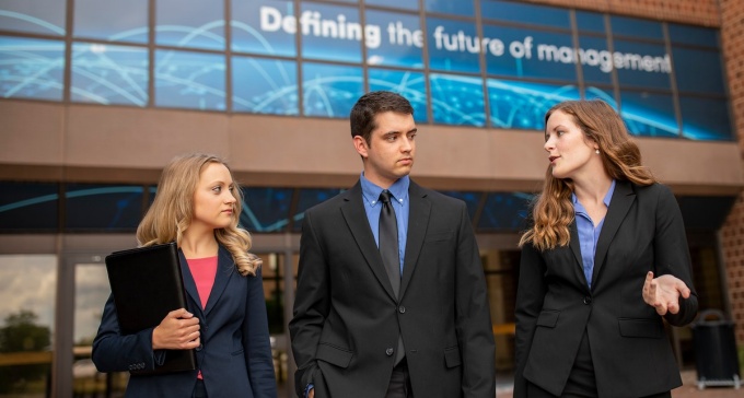Three MBA students walking outside the Jacobs Management Center. 