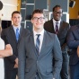 Seven MBA students dressed in professional business attire standing and looking at the camera. 