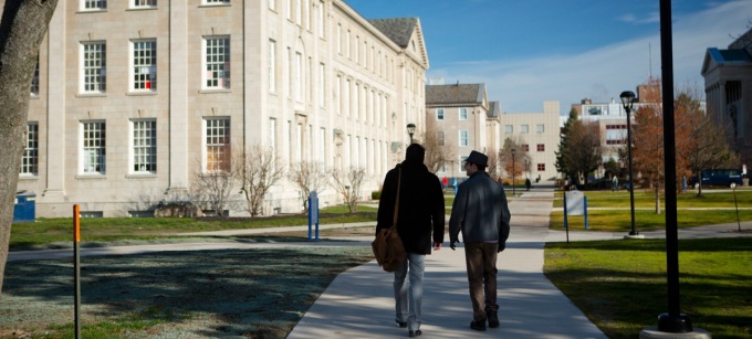 Two students with backs to camera walking in front of Hayes Hall on the South Campus. 
