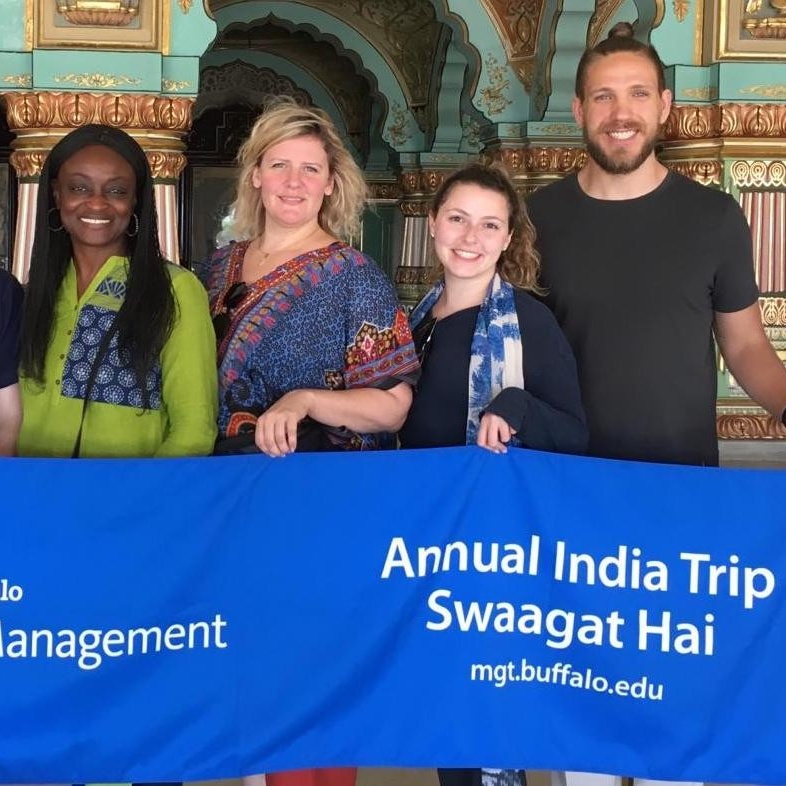 Students and faculty in India standing holding a UB School of Management banner that has text that reads Annual India Trip Swaagat Hai. 