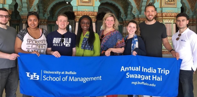 Students and faculty in India standing holding a UB School of Management banner that has text that reads Annual India Trip Swaagat Hai. 