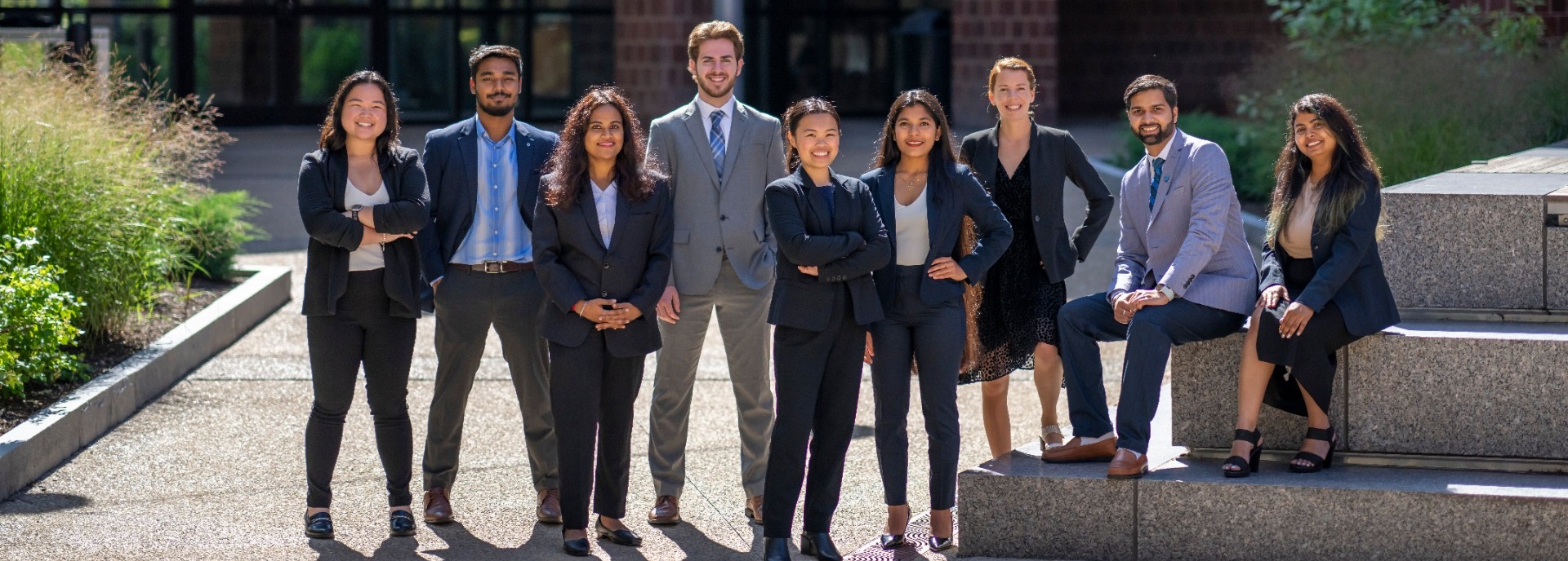 a group of students in business formal wear outside the Jacobs Management Center. 