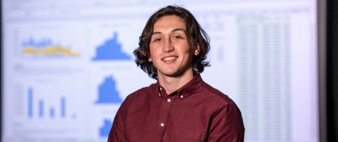 Student standing in front of a data analytics presentation. 