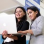 Two female MS Finance students looking at a laptop. 