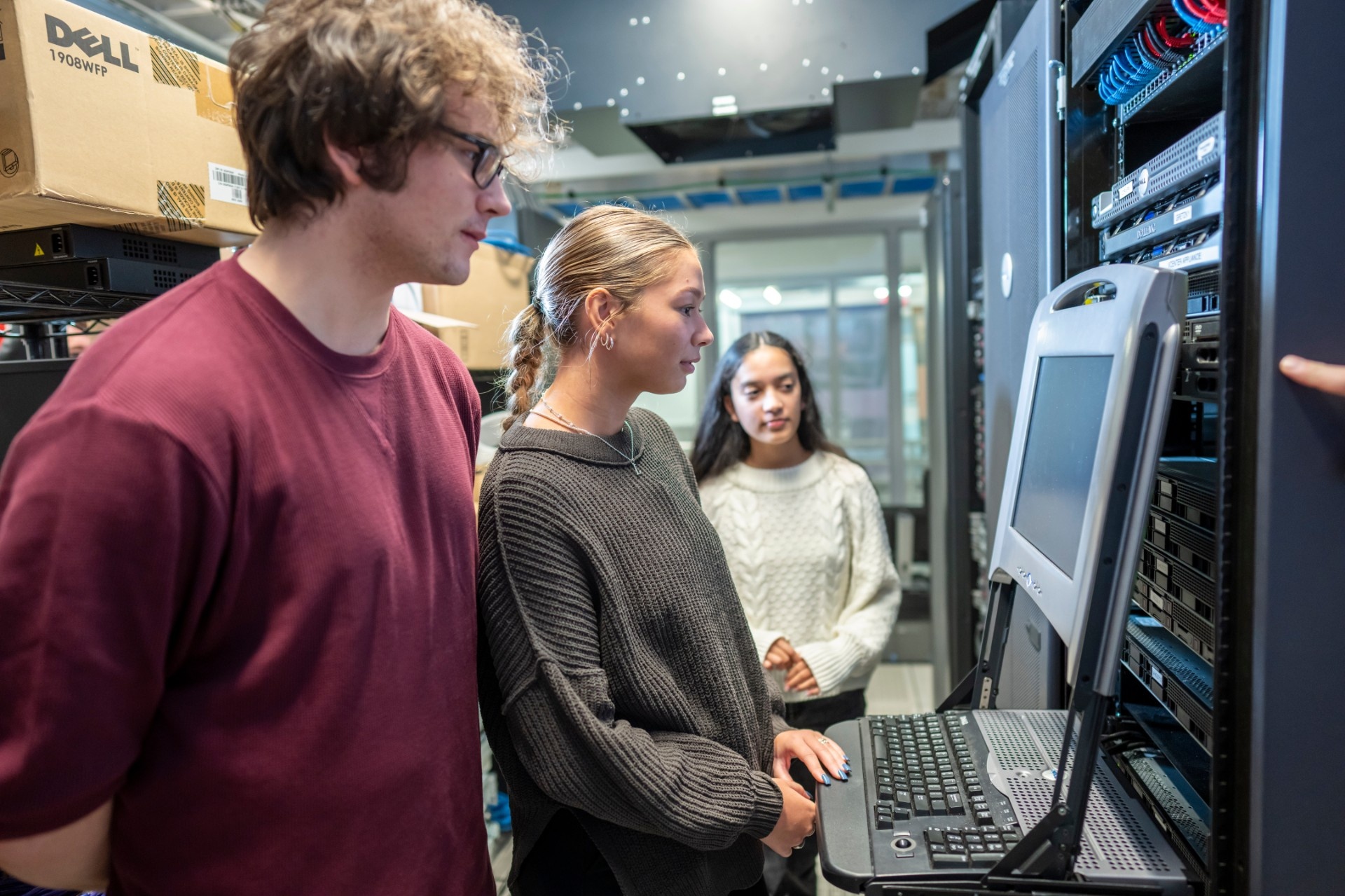 MIS students looking at a computer in the server room. 