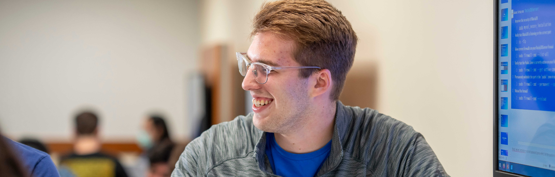 a student smiling while in front of a computer. 