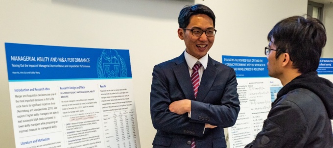Finance PhD student discussing his work at the PhD Showcase poster presentation. 