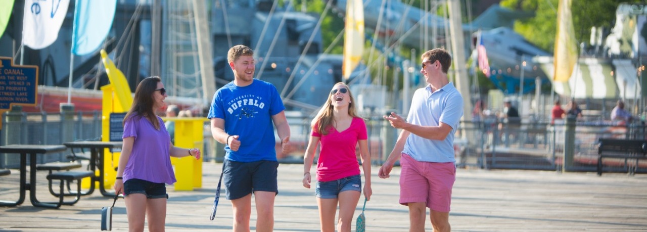 Four individuals walking along the boardwalk at Canalside. 