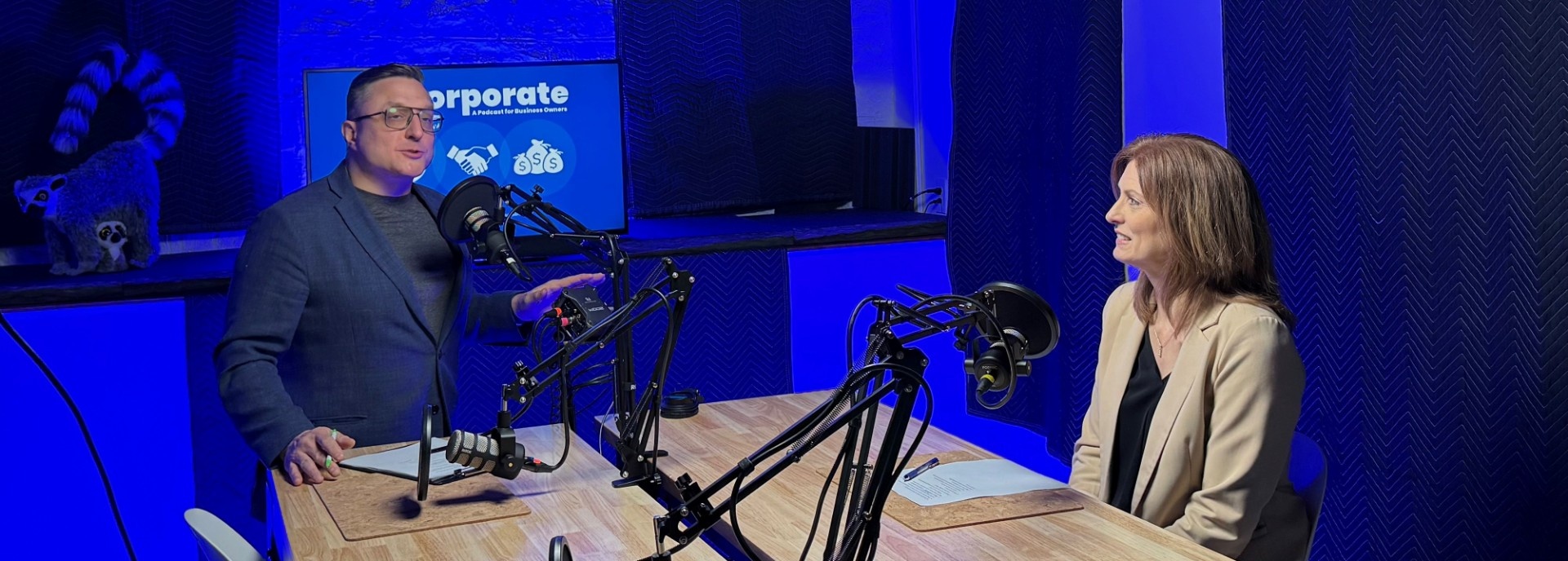 Jordan Lema and Susan Steffan in a podcast sudio with microphones. 