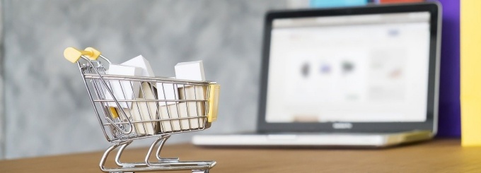 Mini shopping cart in front of laptop. 