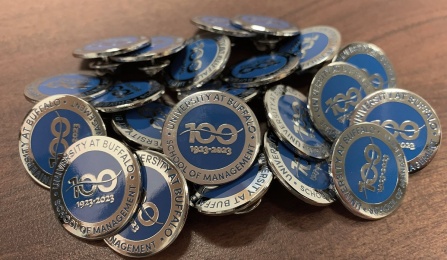 Assortment of centennial pins arranged on a table. 