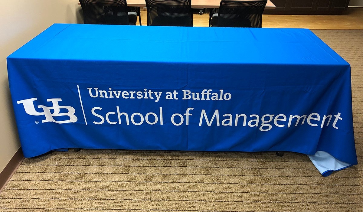 Zoom image: School of Management logo in white on a blue table cloth