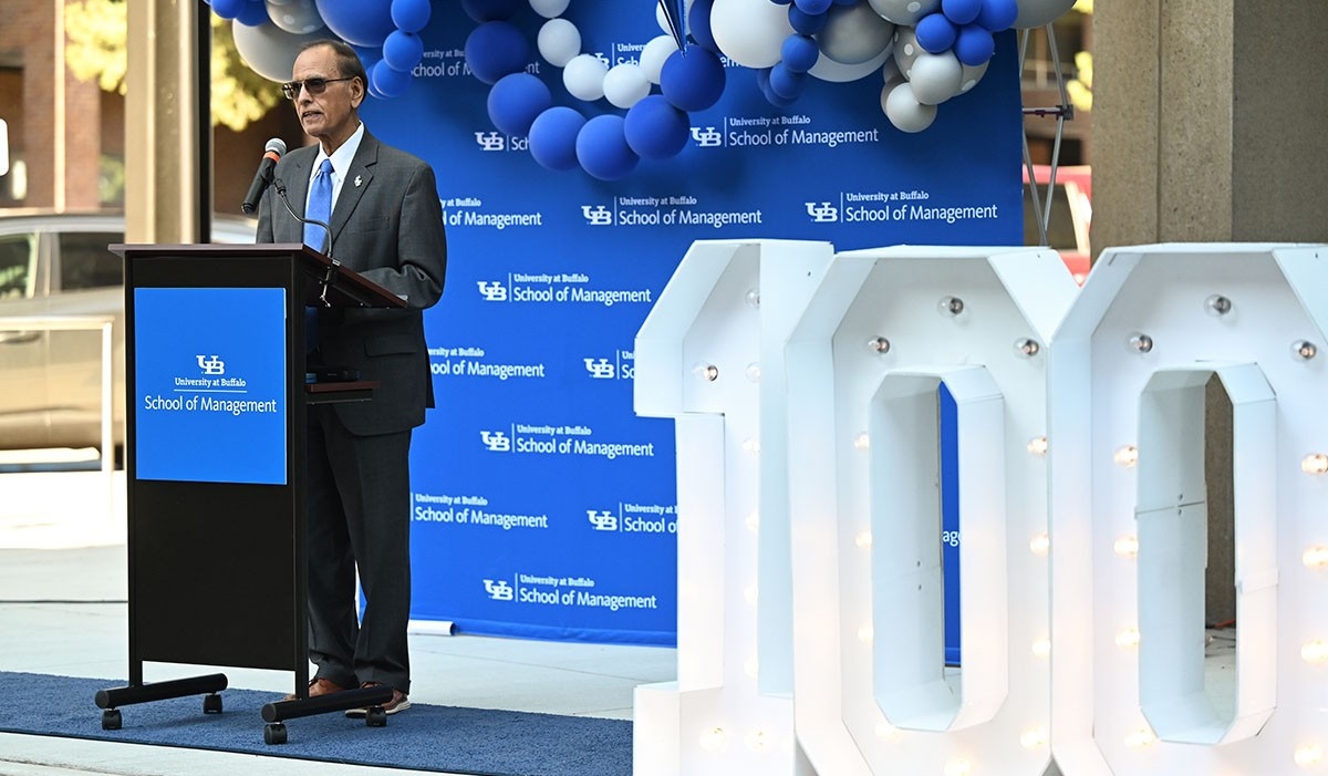Zoom image: President Tripathi speaking at an event behind a lectern..