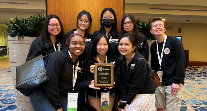 Eight UB students with a plaque recognizing their second-place win in the Best Practices competition. 